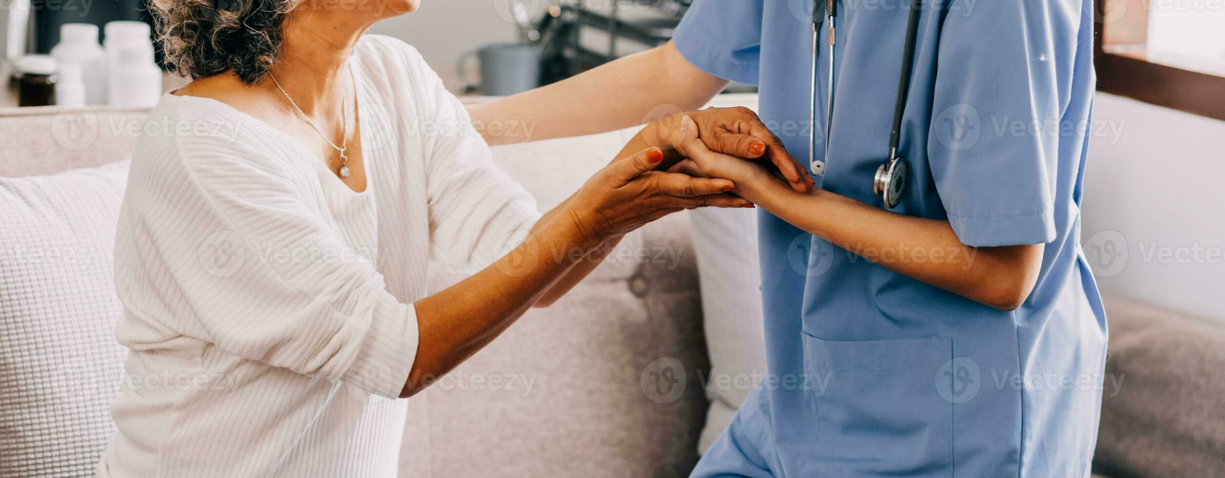 Happy young female nurse provide care medical service help support smiling old grandma at homecare medical visit, lady carer doctor give empathy encourage retired patient sit on sofa at home hospital photo