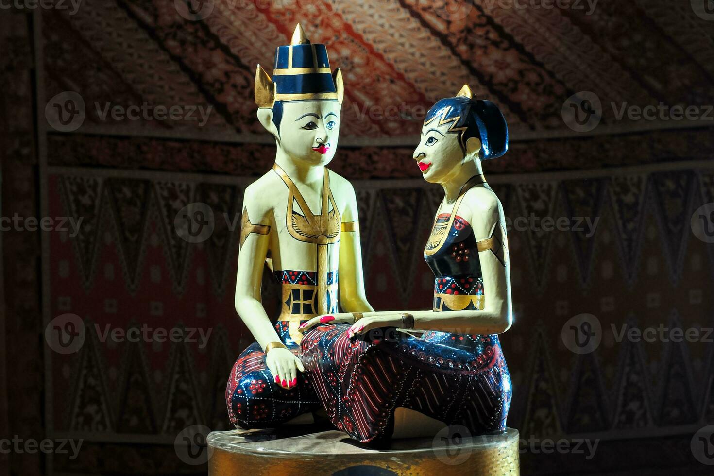 loro blonyo or traditional Javanese wedding dolls sit together on the altar in front of batik cloth photo