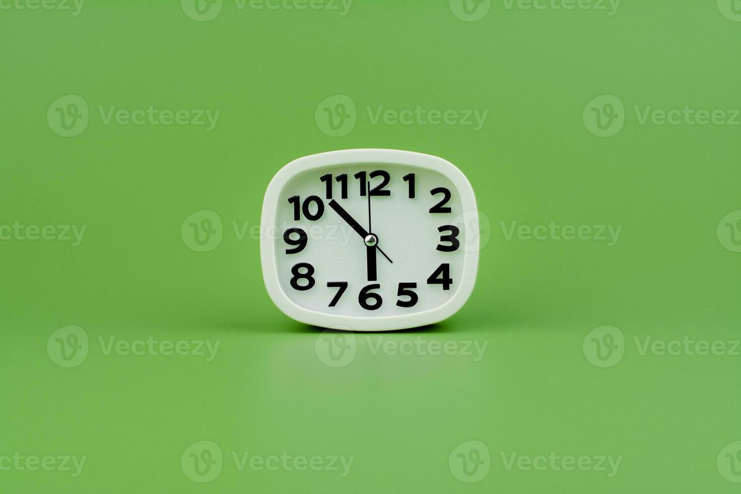 White alarm clock tells time working with time importance of time punctuality White clock on a green background photo