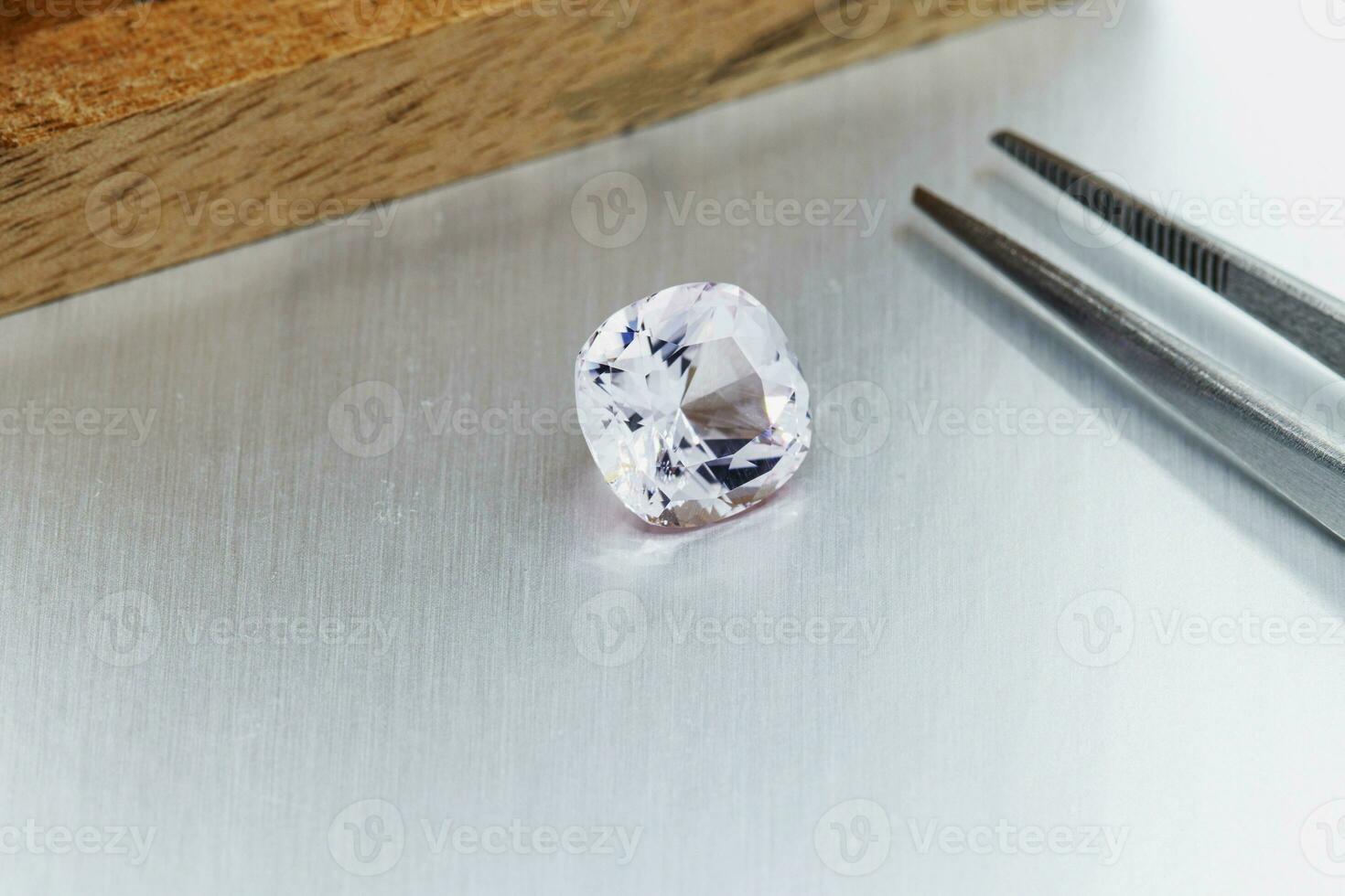 macro mineral faceted stone Morganite with tweezers on a gray background photo
