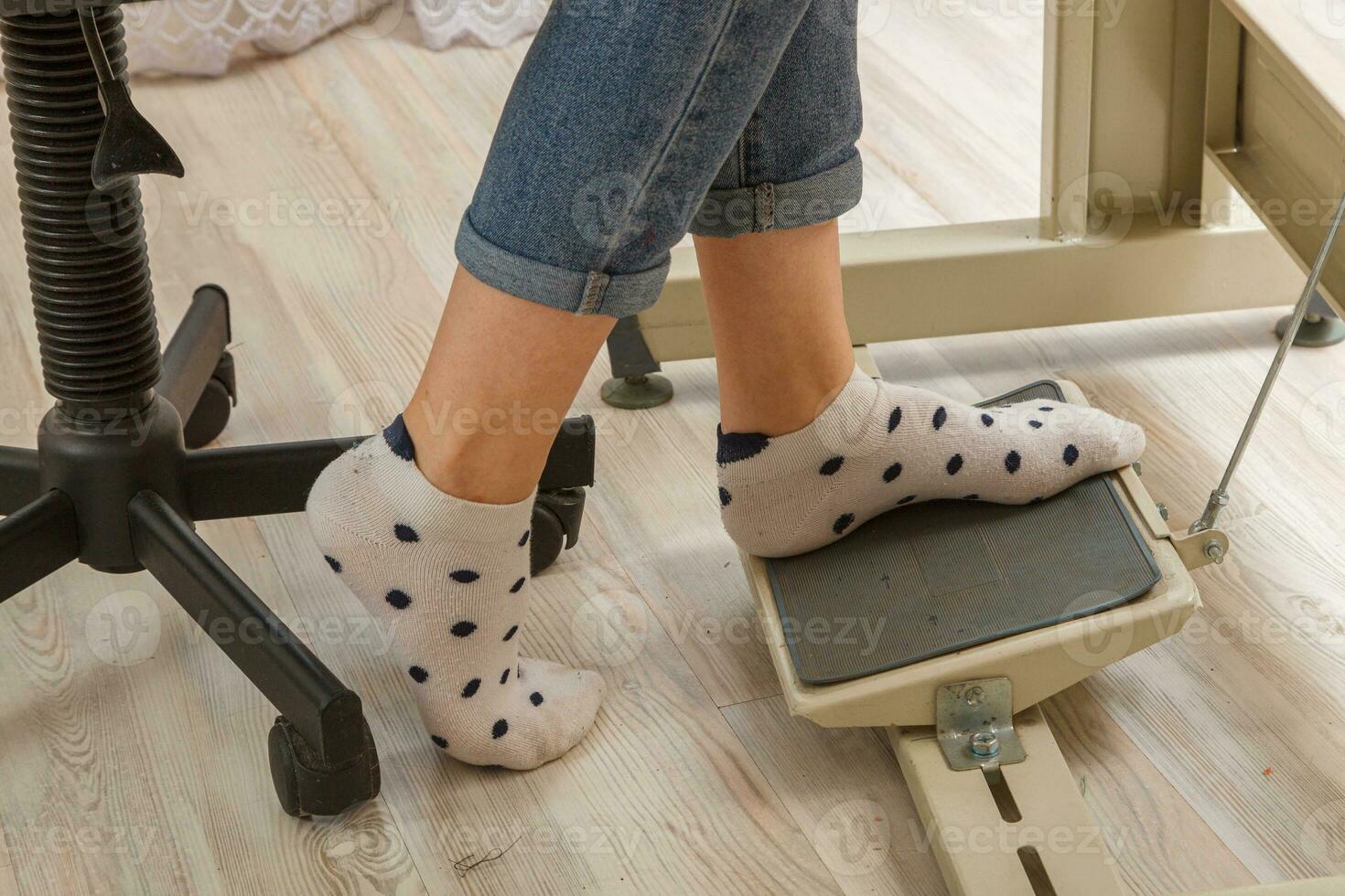 Female feet on the pedal of a sewing machine, motor photo