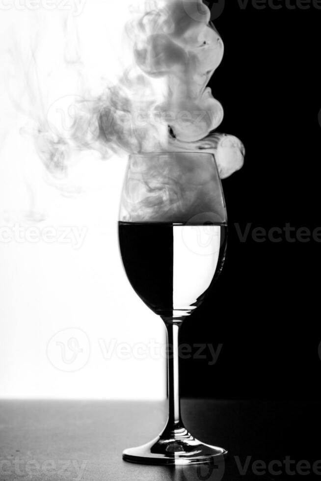 a glass of water and smoke on a black and white background photo