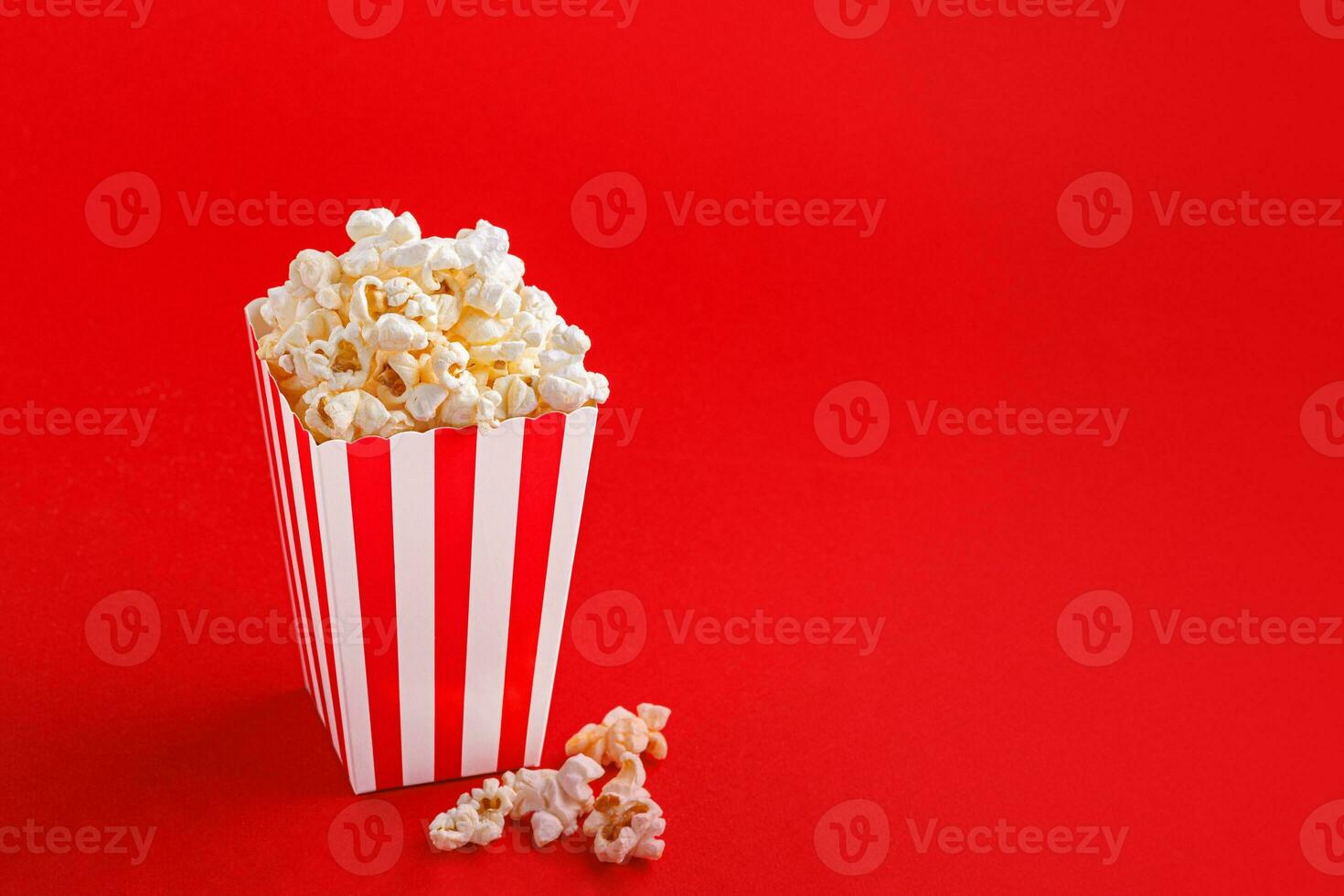 Glass with popcorn on a red background photo