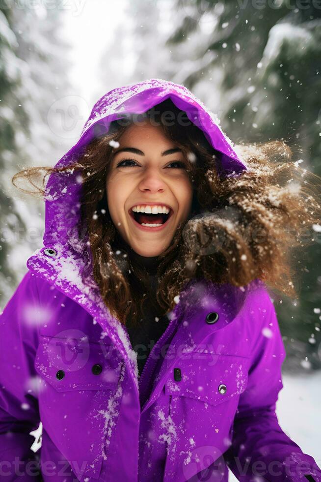 ai generado contento joven Rizado mujer en púrpura Violeta calentar invierno chaqueta riendo disfrutando que cae nieve en Nevado bosque naturaleza caminando y positivo emociones invierno divertido foto