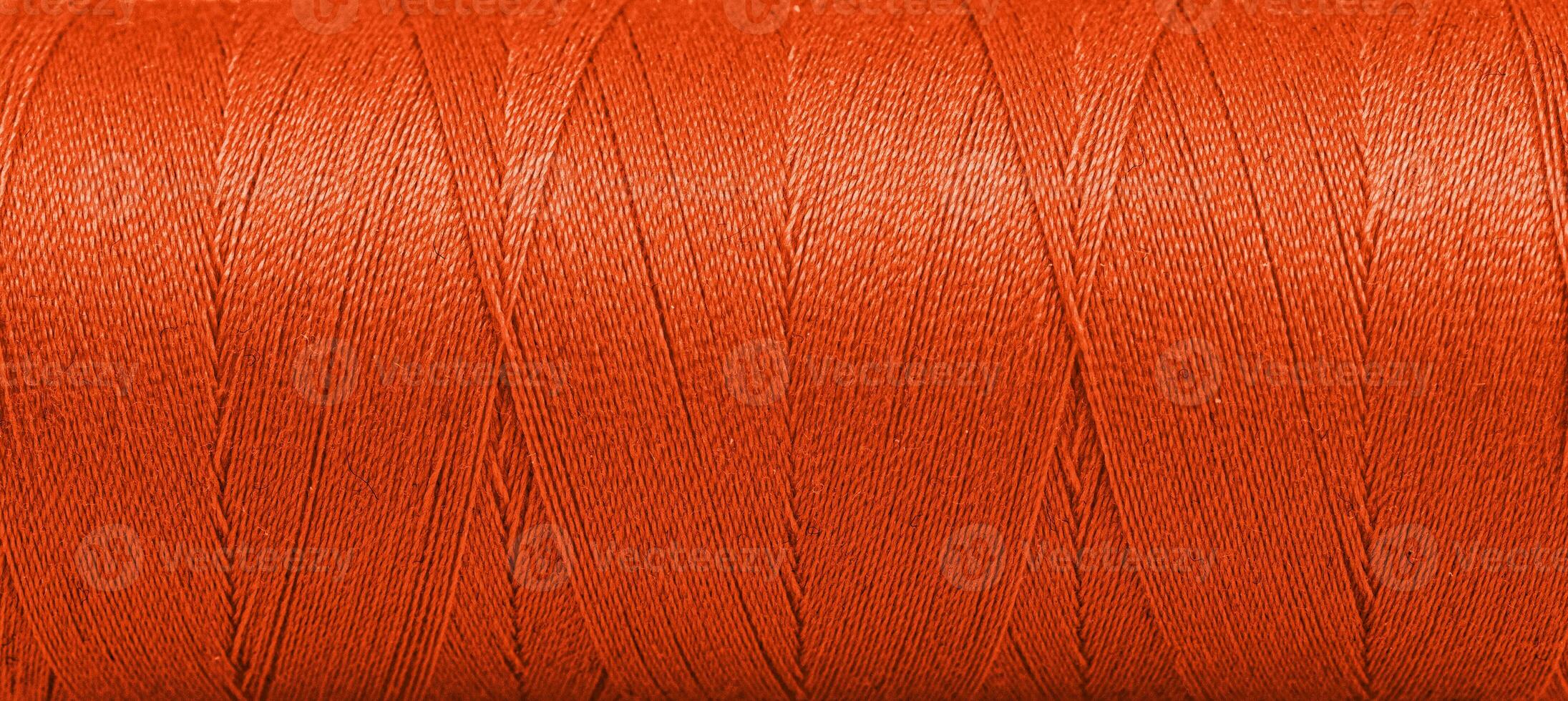 Texture of threads in a spool of Orange color on a white background photo
