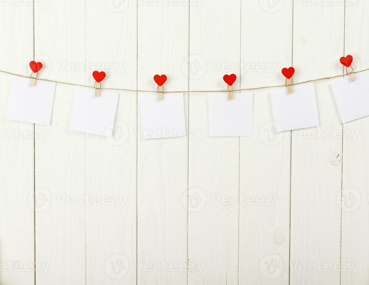 white pieces of paper on clothespins with a heart on a wooden background photo