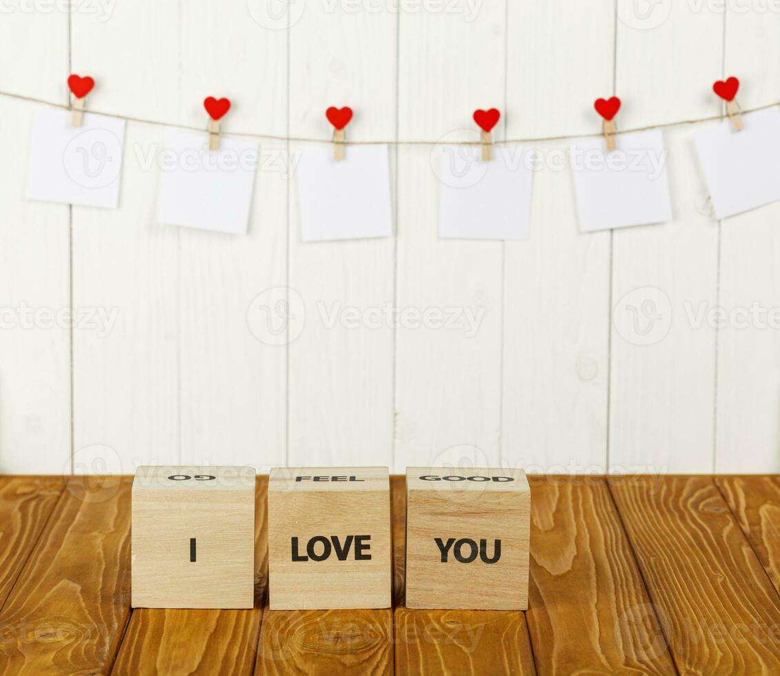 white pieces of paper on clothespins with a heart on a wooden background, a wooden inscription I love you photo