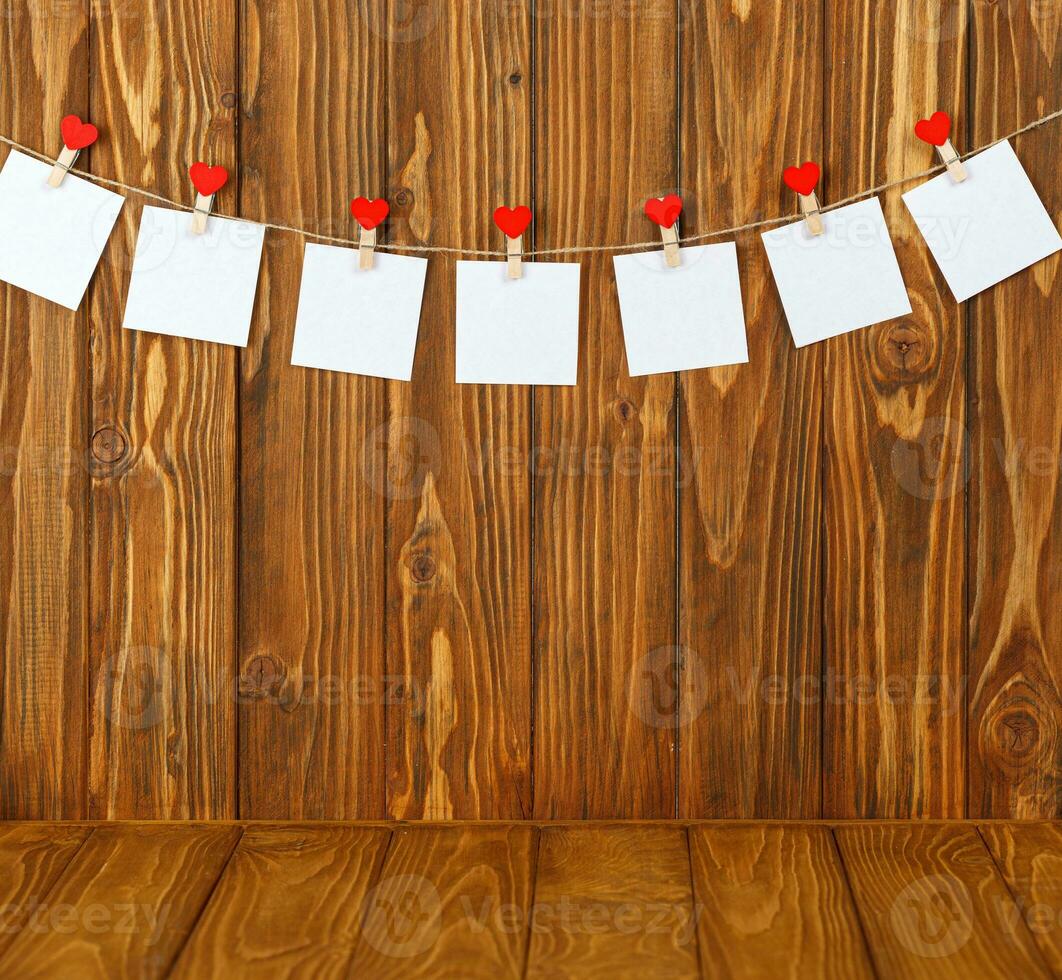 white pieces of paper on clothespins with a heart on a wooden background photo