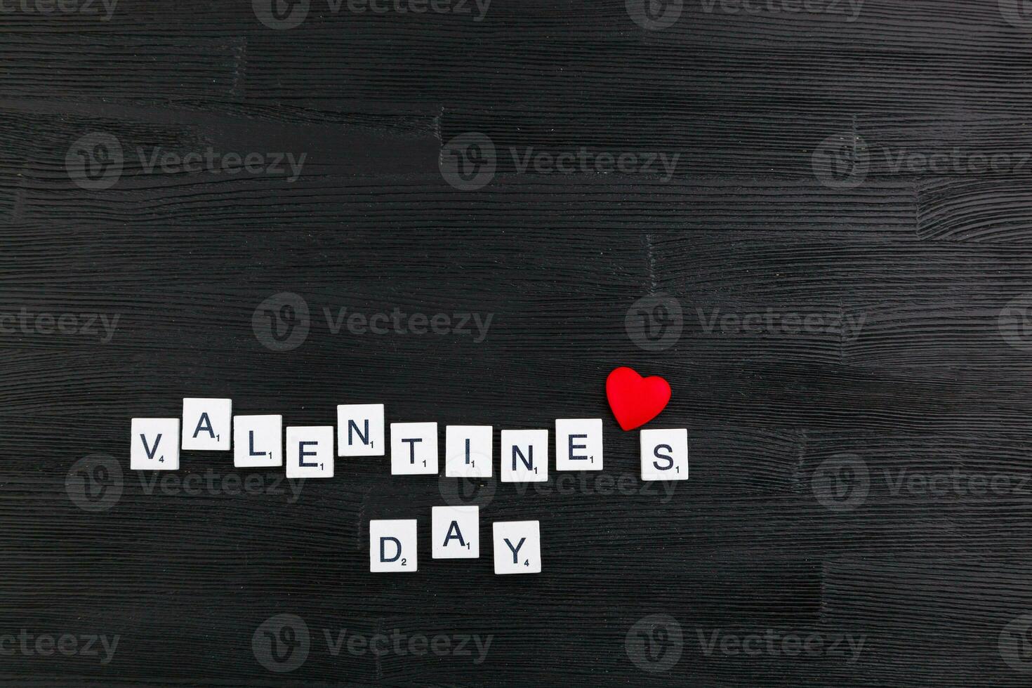 inscription Valentines day on a black wooden background photo