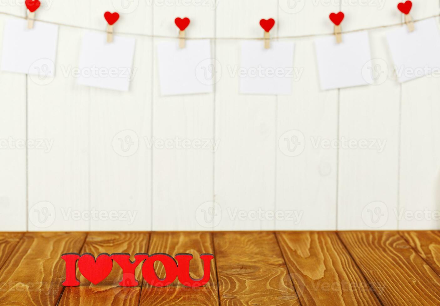 blanco piezas de papel en pinzas para la ropa con un corazón en un de madera fondo, un de madera inscripción yo amor usted foto