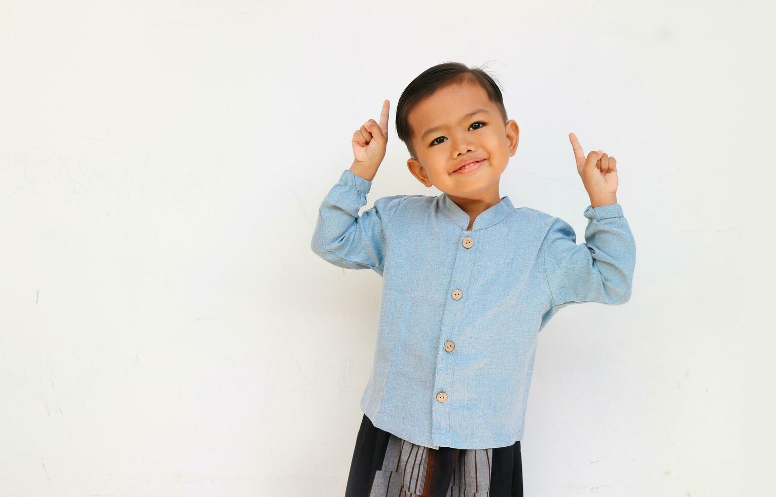 Excited little boy raising his hand and pointing up photo