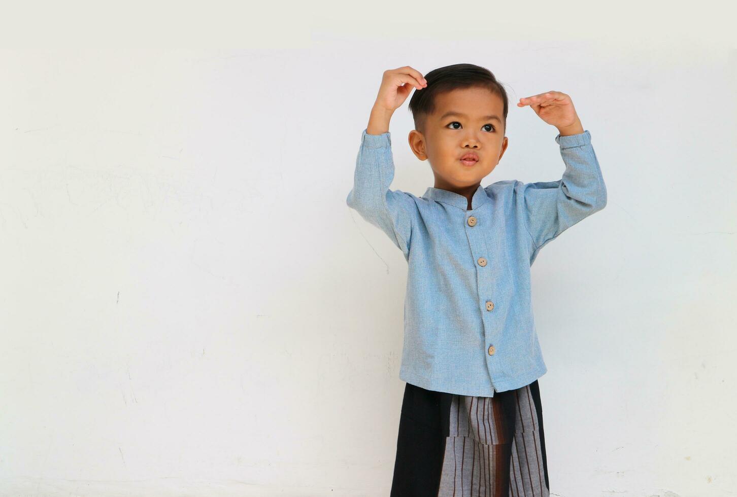 An adorable handsome little boy smiling while raising his hand gesture to playing something. Boy growth photo