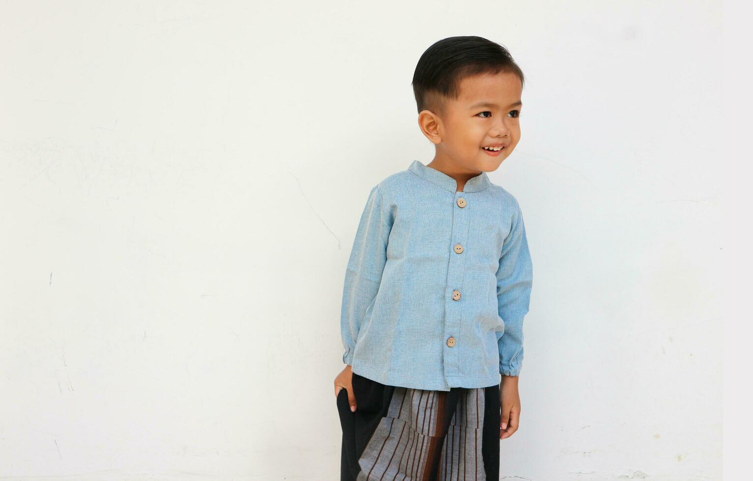 A cute and happy little boy with blue shirt and sarong photo