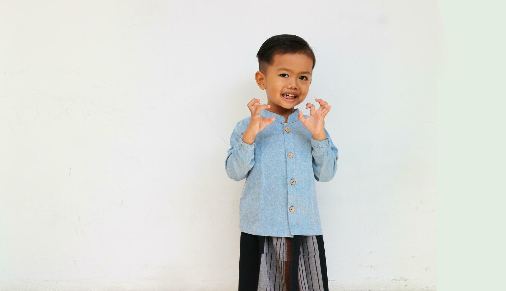 An adorable handsome little boy smiling while raising his hand looking at camera photo