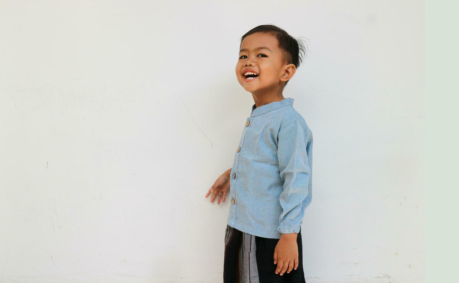 Excited little boy with blue shirt and sarong laughing photo