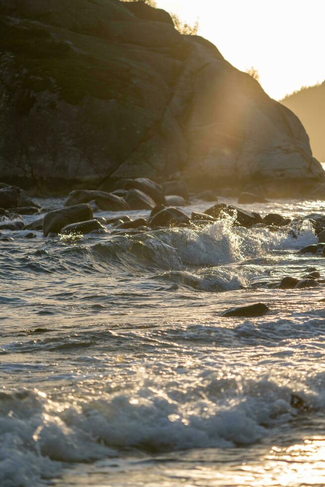 a wave is breaking on the beach with rock in the background photo