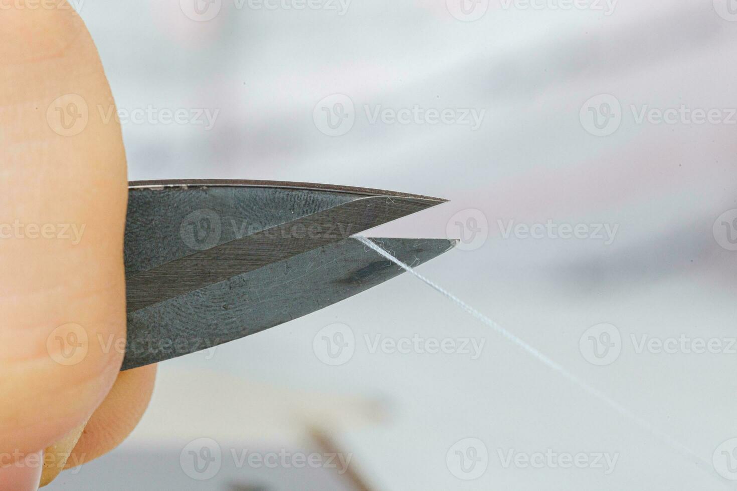 Female hands of a master tailor cuts a thread with scissors photo