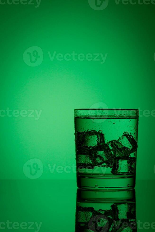 beautiful glass with ice and water on a green background photo