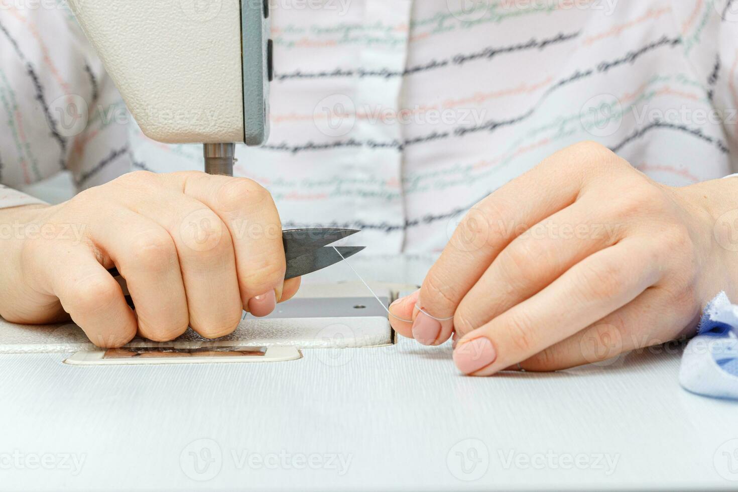 Female hands of a master tailor cuts a thread with scissors photo