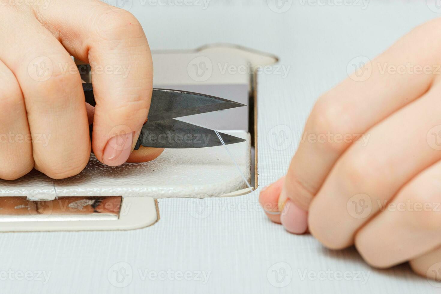 Female hands of a master tailor cuts a thread with scissors photo