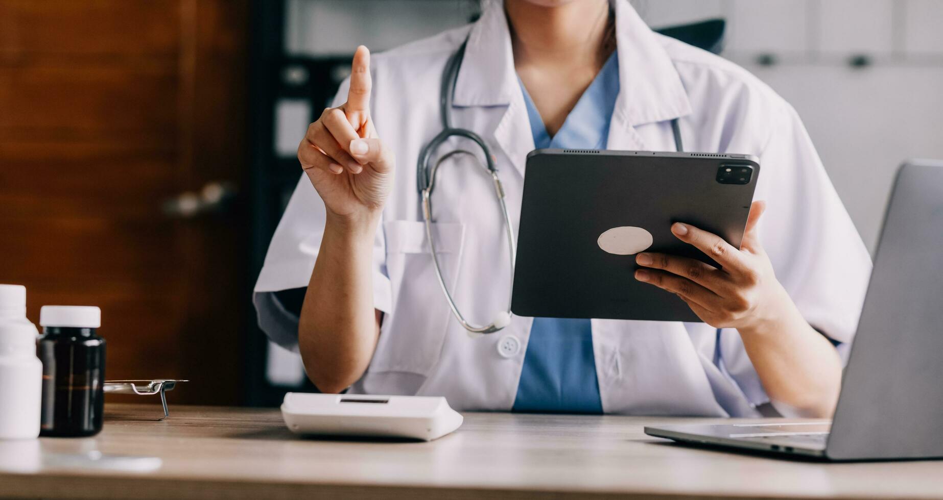 Concerned young female Caucasian doctor in white medical uniform sit at desk in hospital work on laptop, focused woman nurse or GP busy fill anamnesis on computer gadget, medicine, technology concept photo