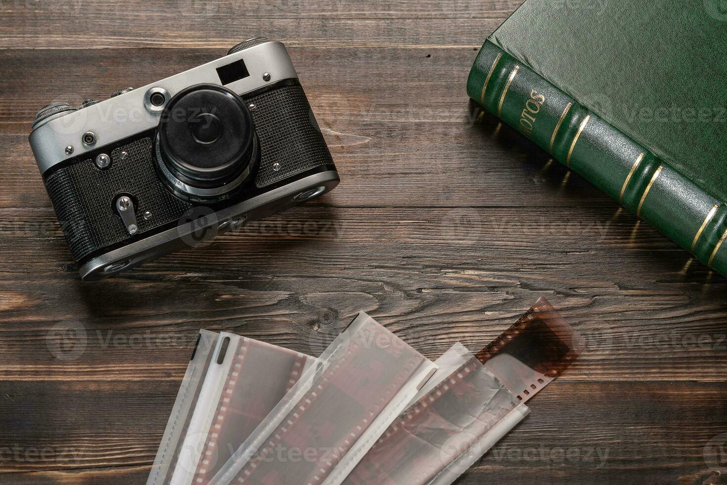 Vintage film camera, film and photo album on a dark wooden table. Top view