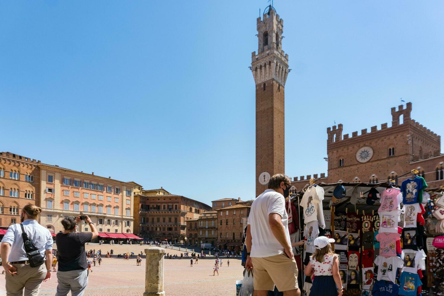 Siena ,Italy-august 10, 2020-Tourists and souvenir shops in Siena near the Campo square during a sunny day photo