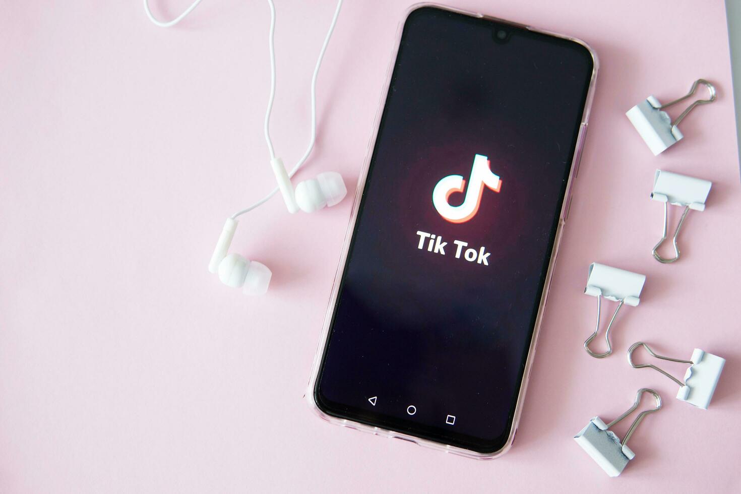 Tver, Russia-April 9, 2020, the tik tok logo on the smartphone screen on pink background with headphones. Tick-Tok icon. logo of the current app. Tiktok social network. photo