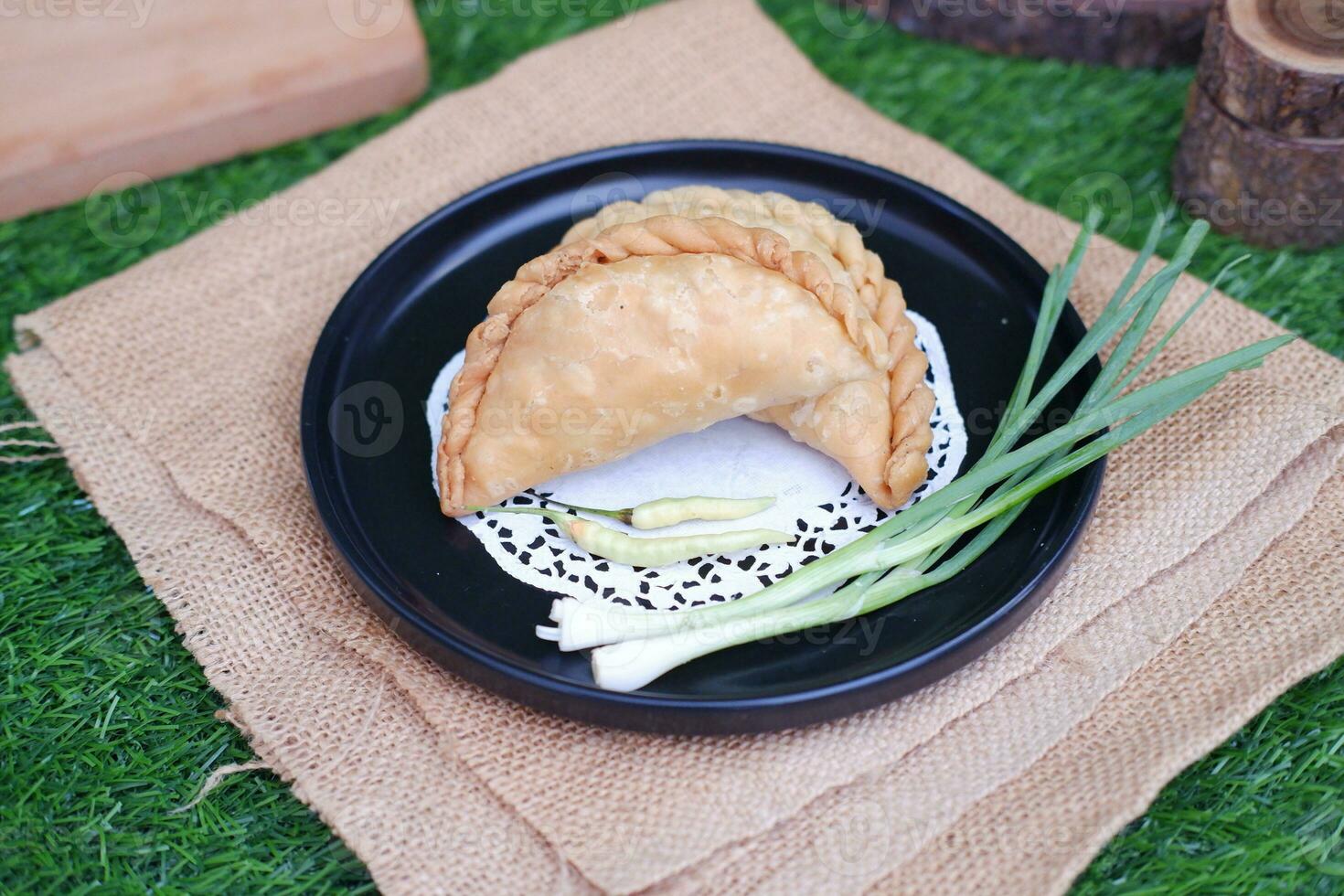 Curry puff or Pastel Goreng is Pastry Popular in Indonesia.fried pastry with filling of sauted vegetable , chicken and boiled egg. accompanied with  sauce or raw chilli pepper photo