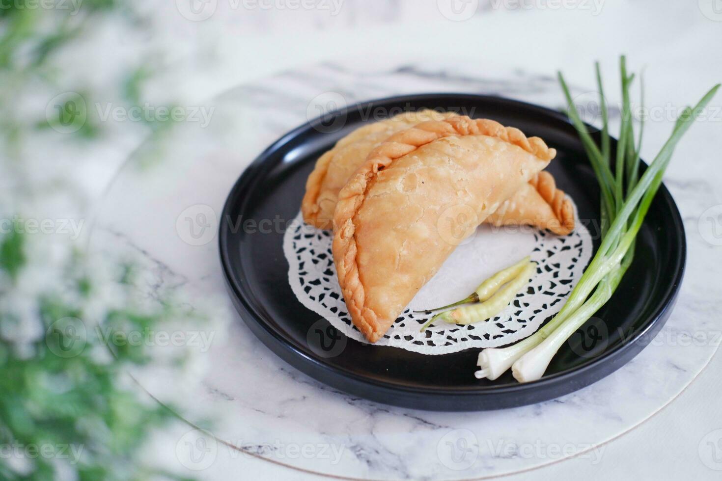 Curry puff or Pastel Goreng is Pastry Popular in Indonesia.fried pastry with filling of sauted vegetable , chicken and boiled egg. accompanied with  sauce or raw chilli pepper photo
