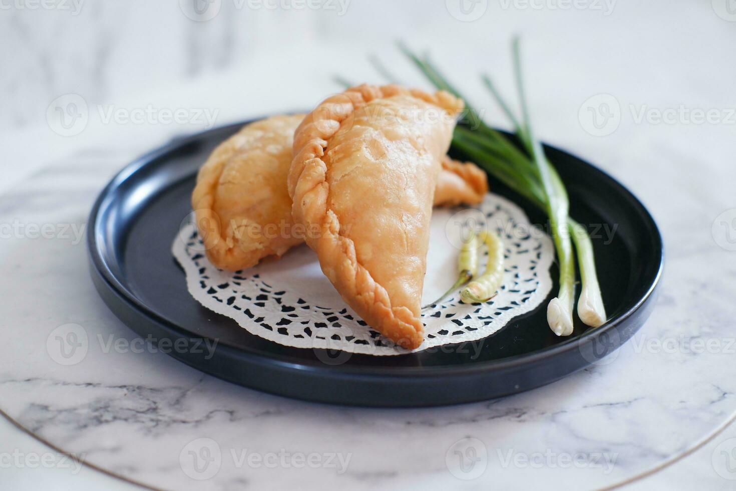 Curry puff or Pastel Goreng is Pastry Popular in Indonesia.fried pastry with filling of sauted vegetable , chicken and boiled egg. accompanied with  sauce or raw chilli pepper photo