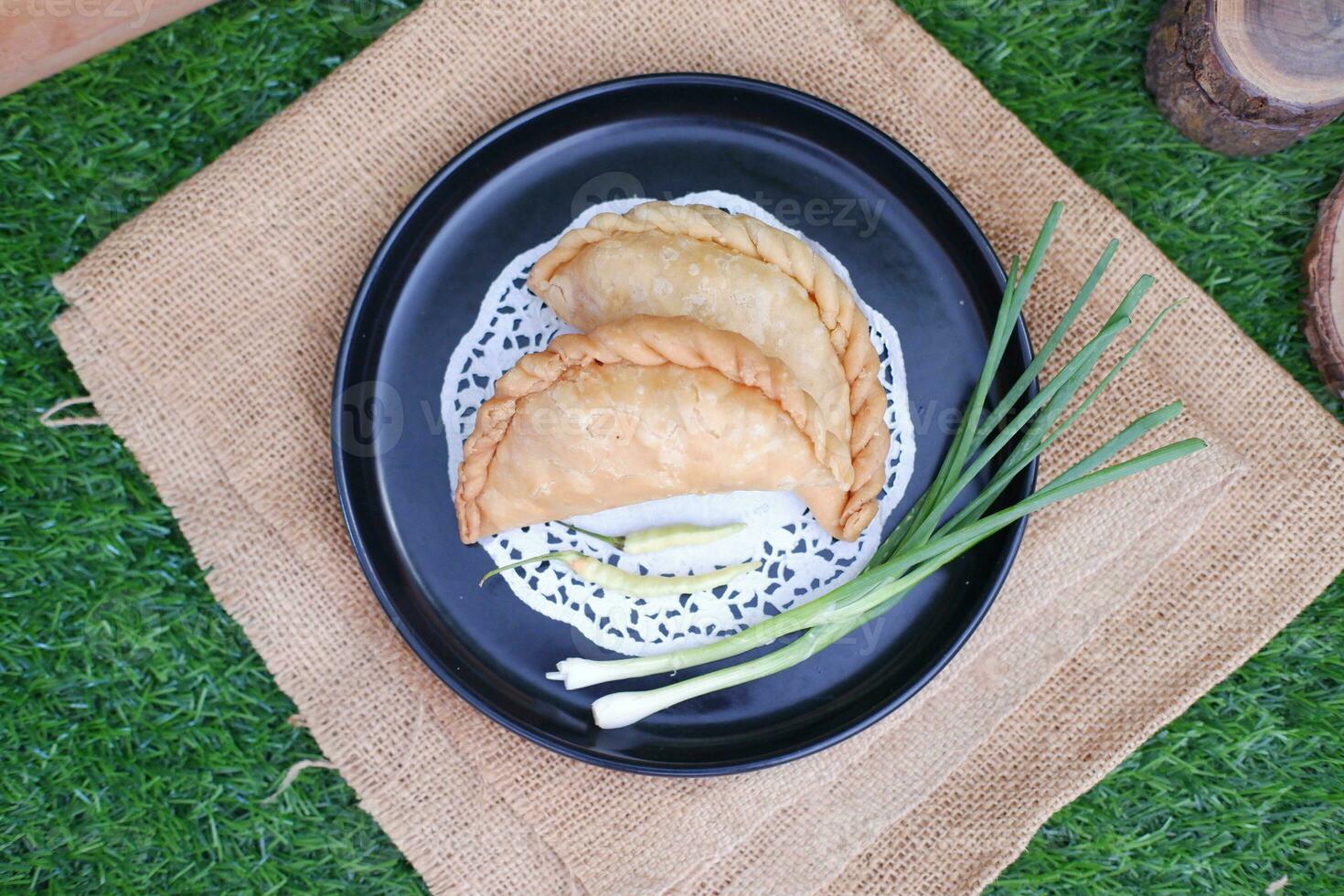 Curry puff or Pastel Goreng is Pastry Popular in Indonesia.fried pastry with filling of sauted vegetable , chicken and boiled egg. accompanied with  sauce or raw chilli pepper photo