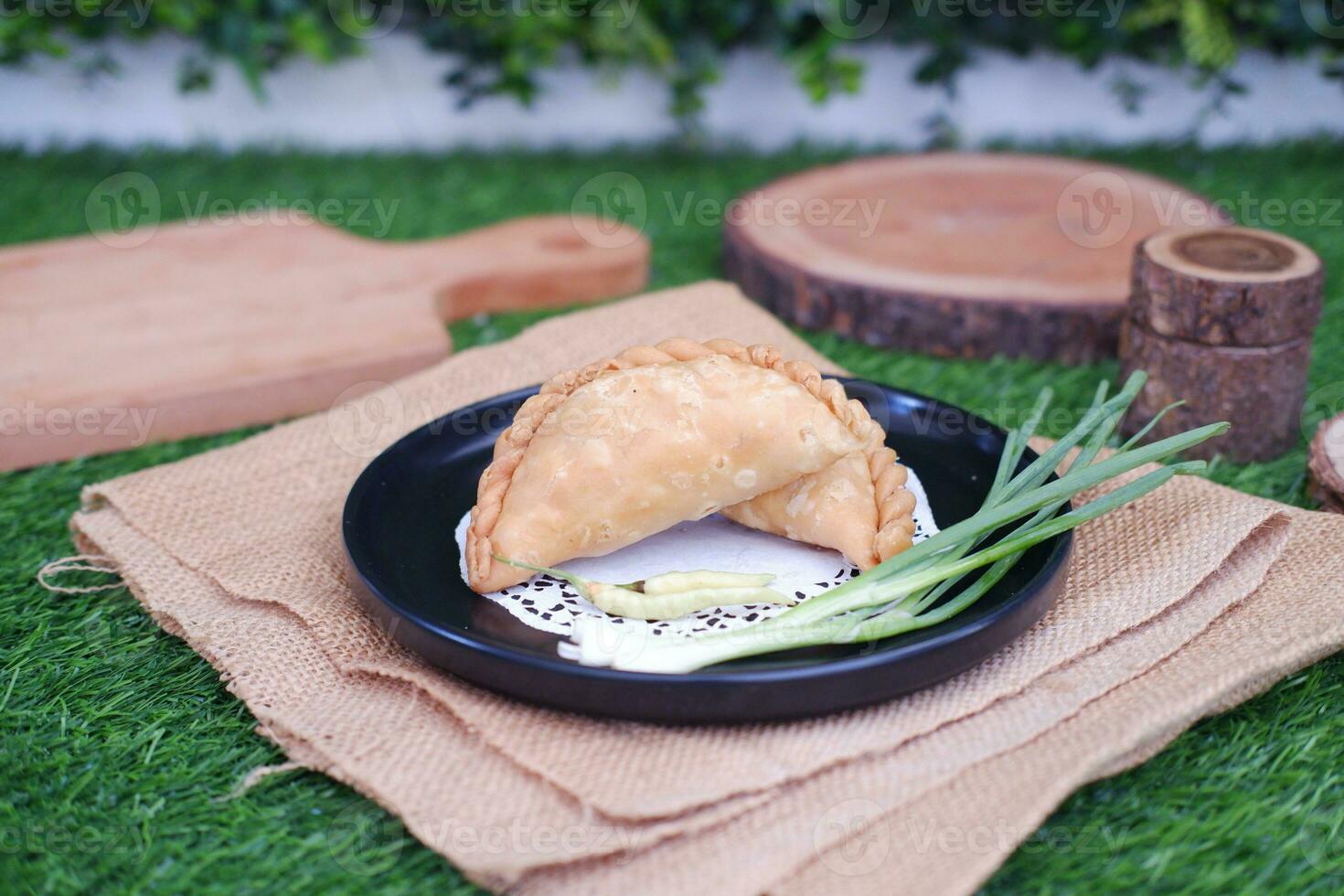 Curry puff or Pastel Goreng is Pastry Popular in Indonesia.fried pastry with filling of sauted vegetable , chicken and boiled egg. accompanied with  sauce or raw chilli pepper photo