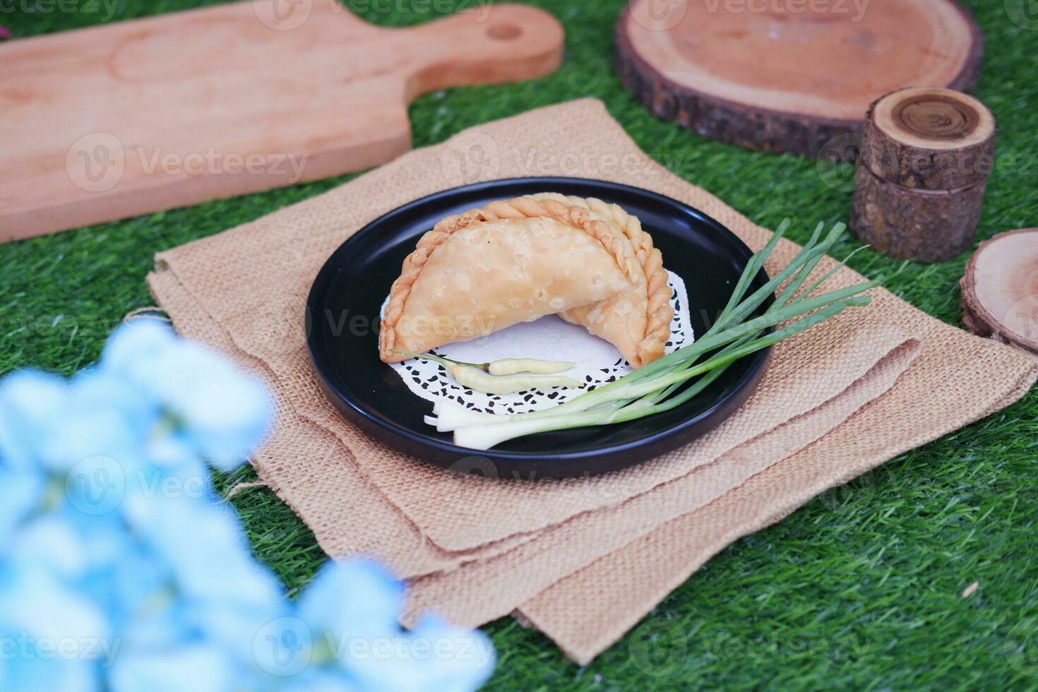 Curry puff or Pastel Goreng is Pastry Popular in Indonesia.fried pastry with filling of sauted vegetable , chicken and boiled egg. accompanied with  sauce or raw chilli pepper photo