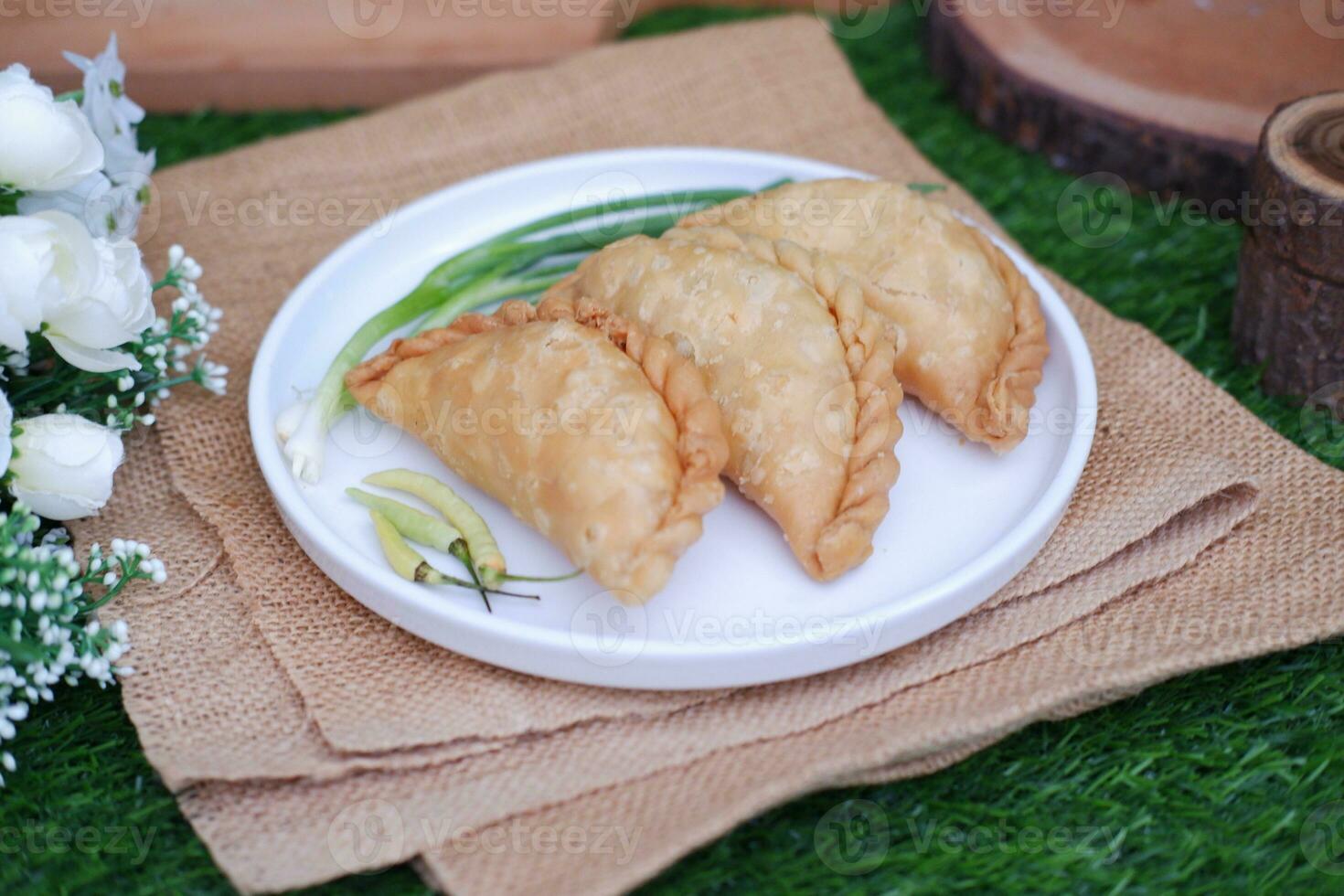 Curry puff or Pastel Goreng is Pastry Popular in Indonesia. fried pastry with filling of sauted vegetable, chicken and boiled egg. accompanied with  sauce or raw chilli pepper photo