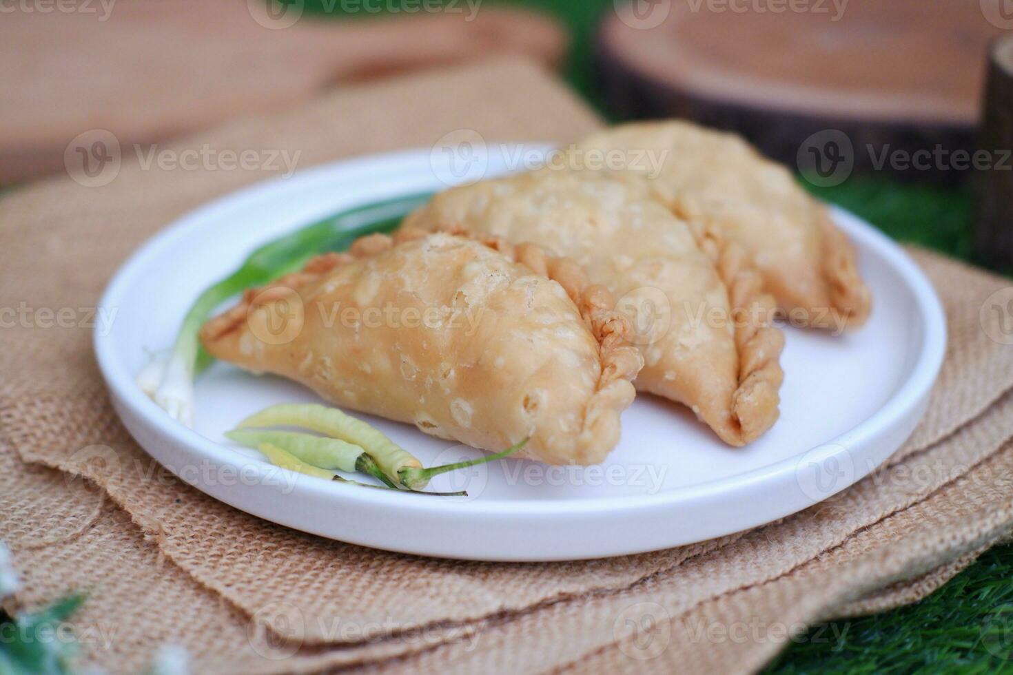 Curry puff or Pastel Goreng is Pastry Popular in Indonesia. fried pastry with filling of sauted vegetable, chicken and boiled egg. accompanied with  sauce or raw chilli pepper photo