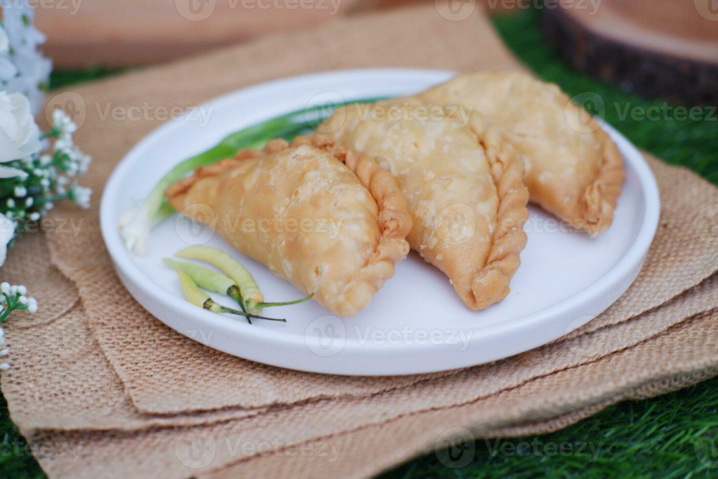 Curry puff or Pastel Goreng is Pastry Popular in Indonesia. fried pastry with filling of sauted vegetable, chicken and boiled egg. accompanied with  sauce or raw chilli pepper photo
