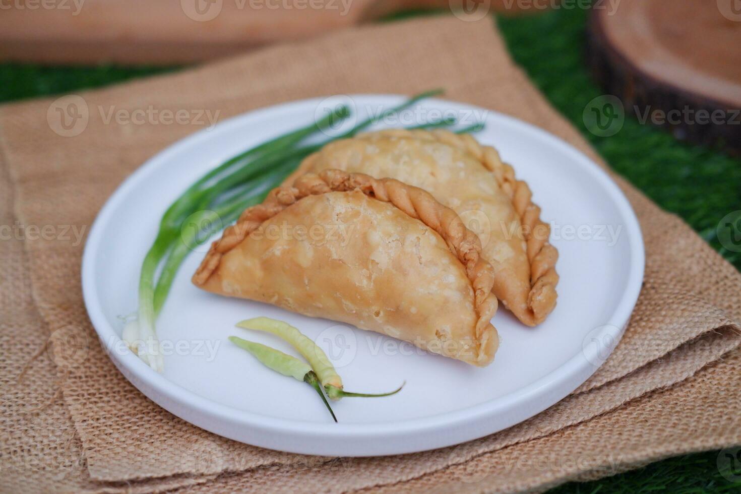 Curry puff or Pastel Goreng is Pastry Popular in Indonesia. fried pastry with filling of sauted vegetable, chicken and boiled egg. accompanied with  sauce or raw chilli pepper photo