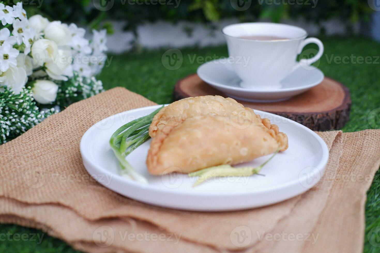 Curry puff or Pastel Goreng is Pastry Popular in Indonesia. fried pastry with filling of sauted vegetable, chicken and boiled egg. accompanied with  sauce or raw chilli pepper photo