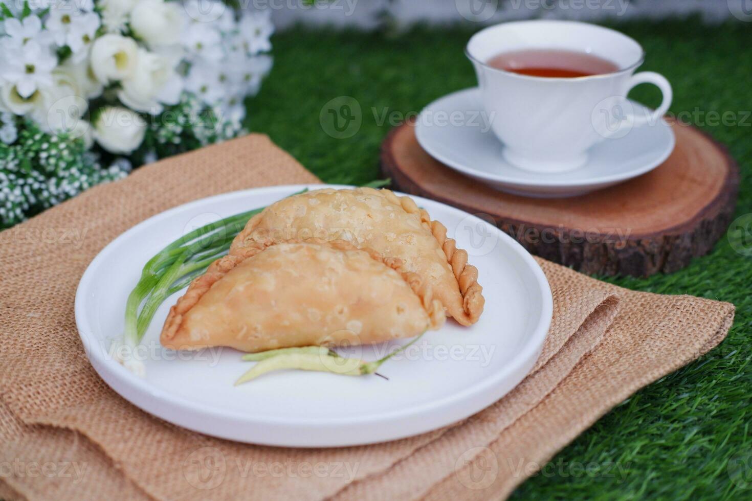 Curry puff or Pastel Goreng is Pastry Popular in Indonesia. fried pastry with filling of sauted vegetable, chicken and boiled egg. accompanied with  sauce or raw chilli pepper photo
