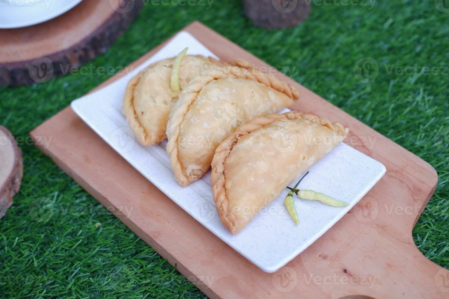 Curry puff or Pastel Goreng is Pastry Popular in Indonesia. fried pastry with filling of sauted vegetable, chicken and boiled egg. accompanied with  sauce or raw chilli pepper photo