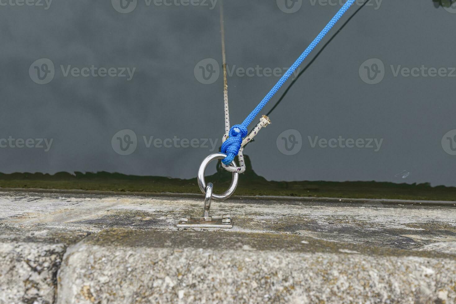 Picture of an eyelet for mooring ships at the pier with a line in front of dark water photo