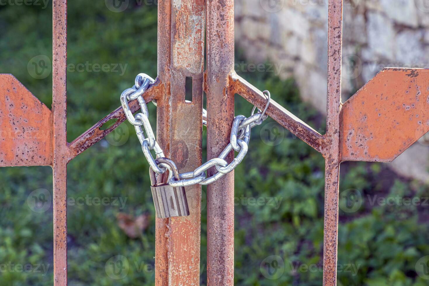 Close-up of a lock with a chain that closes a metal gate photo