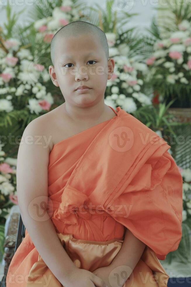 portrait of buddhist novice wearing thai monk clothes standing outdoor photo