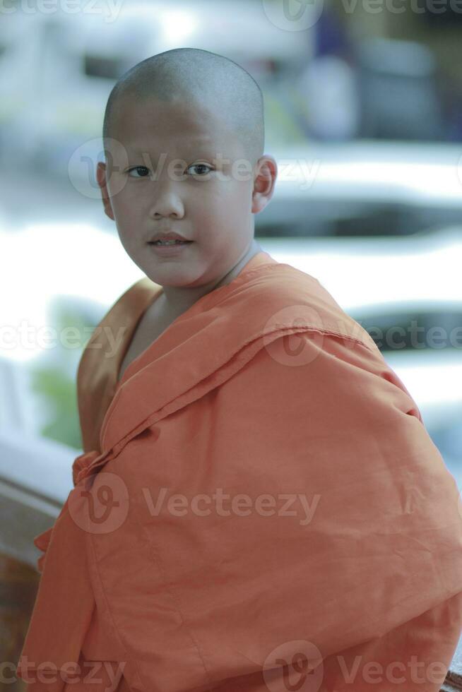 portrait of buddhist novice wearing thai monk clothes standing outdoor photo