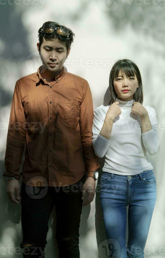 portrait of asian younger man and woman like fashion model standing against beautiful light wall photo