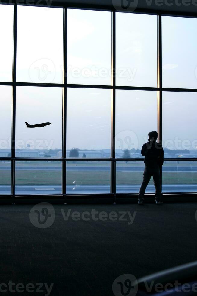 silueta de un hombre en pie en frente de el ventana a el aeropuerto foto