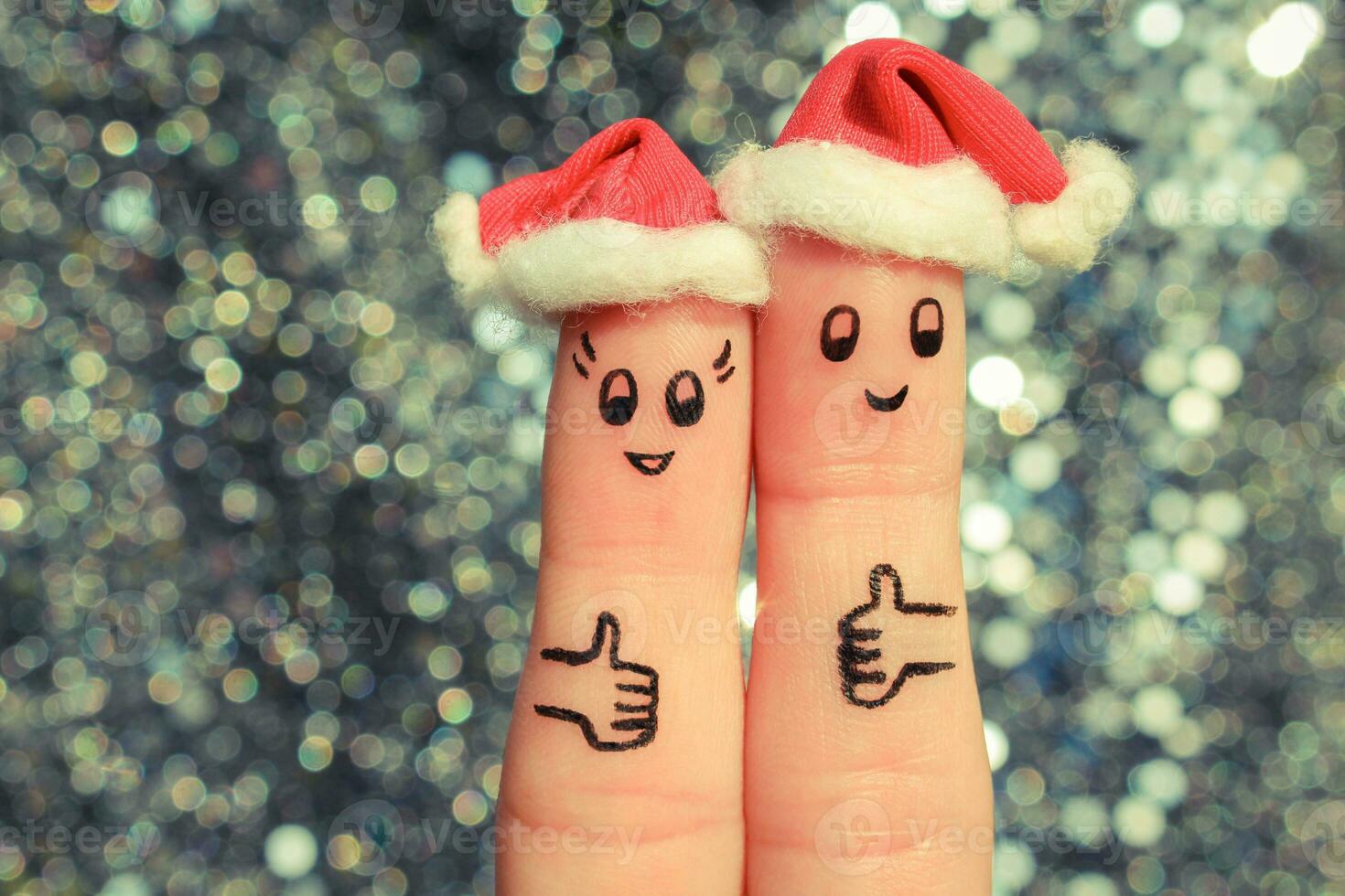 Finger art of couple celebrates Christmas. Concept of man and woman laughing in new year hats. Happy pair showing thumbs up. Toned image. photo