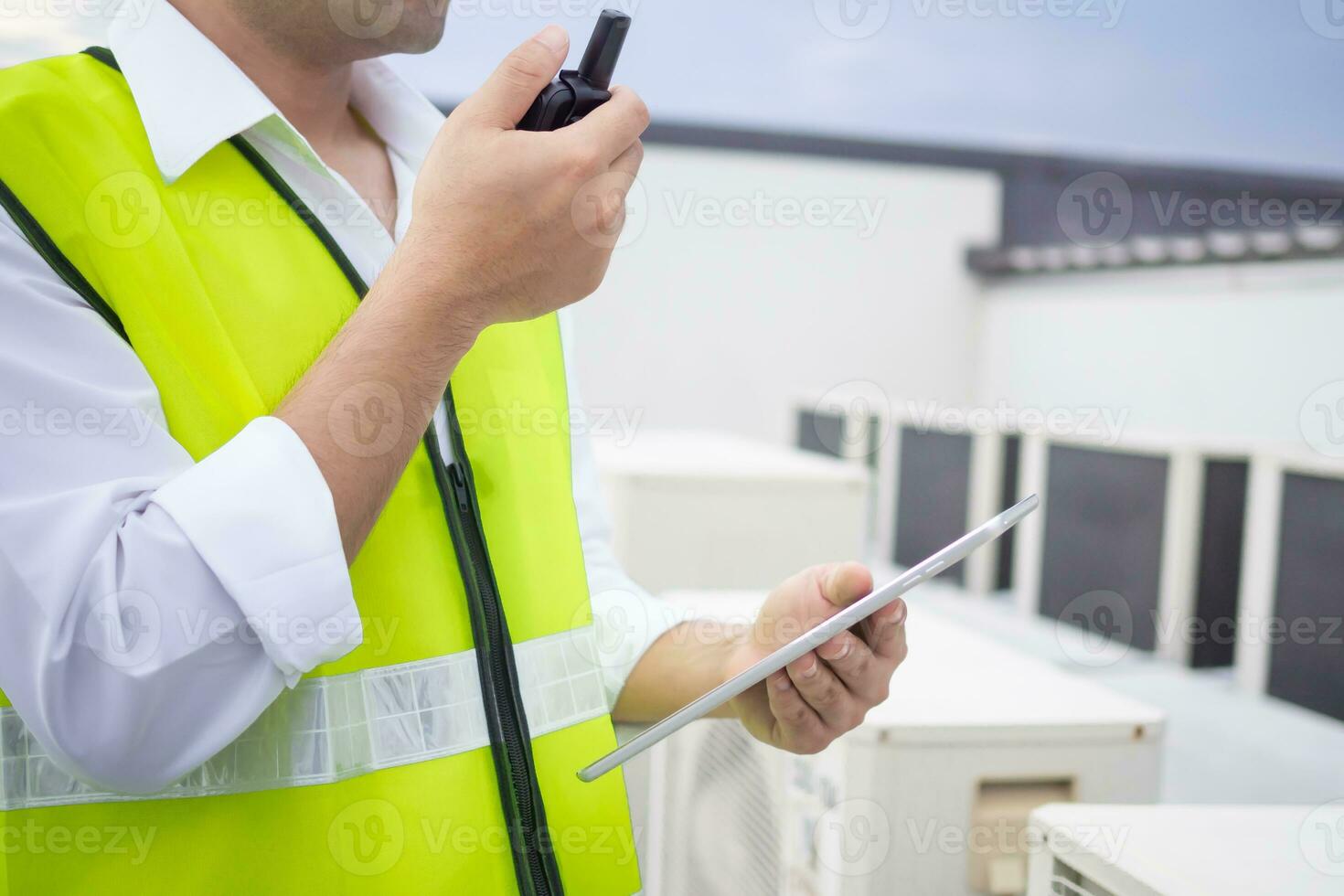 Asian maintenance engineer works on the roof of factory. contractor inspect compressor system and plans installation of air condition systems in construction. technology, online, mobile application. photo