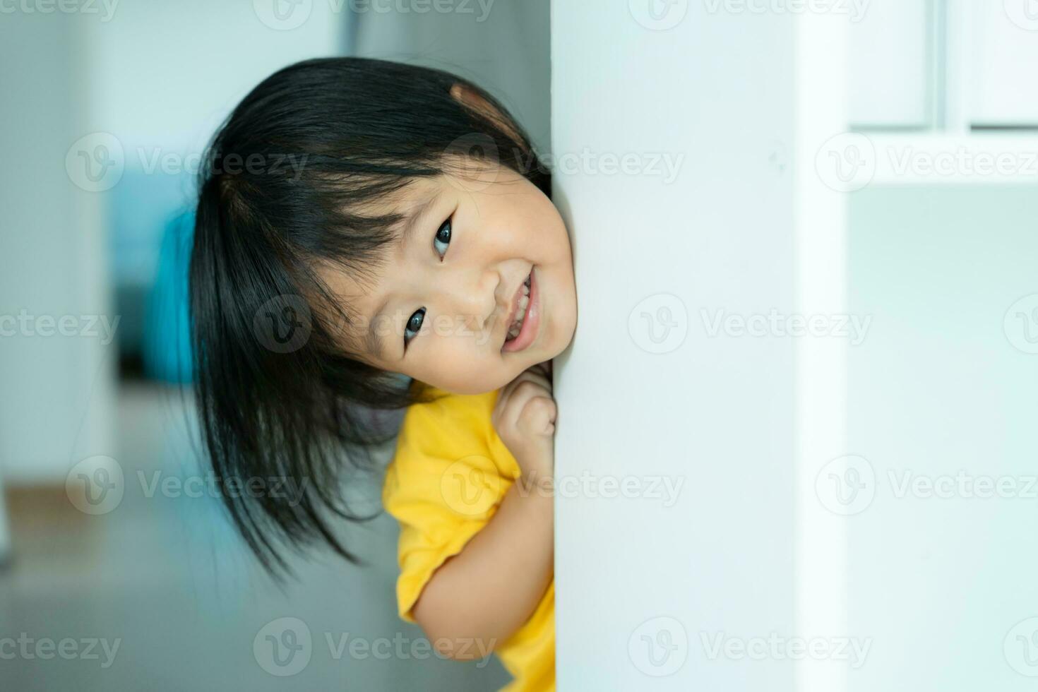 little asian children kid playing hide and seek standing next wall house, Adorable child having fun in the home. happy family have fun with kids, activity, learning, activity, game, meditation photo